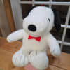 Plush Snoopy toy with a red bow tie sitting on a pink box