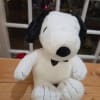 Plush Snoopy stuffed animal sitting on a wooden surface