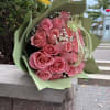 Pink rose bouquet wrapped in pale green paper with a ribbon