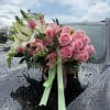 Pink rose and lily bouquet with ribbon on a car hood