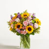 Bouquet of sunflowers, pink roses, and purple flowers in a glass vase