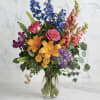 Colorful bouquet with roses, lilies, delphinium, and snapdragons in a glass vase