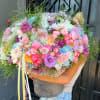 Large pastel bouquet in a gray bucket with pink, white, and purple flowers