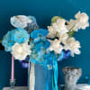 Blue and white floral arrangement in a tall blue box with ribbons