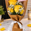 Yellow roses with white baby's breath wrapped in brown paper and tied with a ribbon