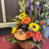 Pumpkin-shaped floral arrangement with orange roses and yellow daisies