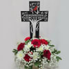 Red and white sympathy arrangement beneath a memorial cross sign