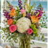 A large white hydrangea crowns this mixed-color arrangement, giving it a breezy