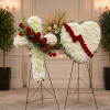 A white floral cross and matching white heart, each mounted on a