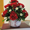 Red carnations and white daisies in a baseball-shaped vase