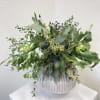 Green foliage arrangement in a ribbed white vase
