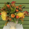 Urn arrangement of orange wildflowers . Fern curls and dracaena foliage make