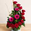 Red roses and pink gerbera daisies arranged in a glass vase