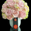 Pink rose bouquet in a pale blue vase with a black ribbon tag