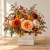 Autumn floral arrangement in a white wooden box with orange and peach blooms