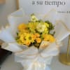 Yellow and white bouquet wrapped in white paper with gold trim