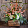 Peach gladiolus and white hydrangeas arranged in a wooden crate