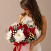 Woman holding a bouquet of red roses and white chrysanthemums in a pink box
