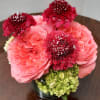 Pink and red floral arrangement in a dark vase