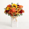Bouquet of sunflowers, roses, and mums in a white vase with a ribbon