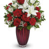 Red roses and white lilies arranged in a tall burgundy vase