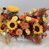 Low rectangular arrangement of sunflowers, roses, and fall-toned blooms in a whitewashed wooden box.