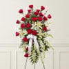 Tall standing floral spray with red roses, white lilies, and a white ribbon