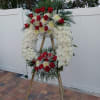 Standing funeral wreath of red roses and white flowers on an easel
