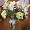 White lilies and pink roses in a glass vase with hydrangeas