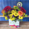 Bright mixed flower arrangement in a birthday gift box with a colorful topper