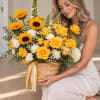 Woman holding a basket of yellow roses, sunflowers, and white flowers