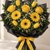 Yellow roses and gerbera daisies with tulips in black wrap and a yellow ribbon