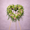 Heart-shaped standing wreath of pink roses and green flowers on a wooden easel