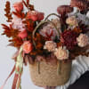 Basket arrangement of pink roses and burgundy chrysanthemums