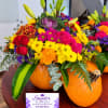 Colorful mixed flower arrangement in pumpkins with a business card in front