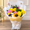 Bouquet of yellow, pink, white, and purple flowers wrapped in white paper