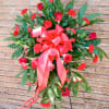 Standing floral spray with red roses and carnations, tied with a large red ribbon