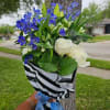 Bouquet of white roses and blue flowers wrapped in black-and-white paper