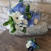 Blue and white bouquet with daisies and roses in a textured silver clutch