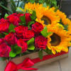 Boxed arrangement of red roses and yellow sunflowers with a red ribbon