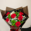 Bouquet of red roses with baby's breath wrapped in dark paper