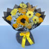 Yellow bouquet with roses, daisies, and a sunflower in black wrap