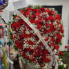 Large heart-shaped red rose and carnation arrangement with a white ribbon