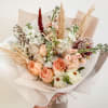 A romantic hand-tied bouquet featuring peach garden roses, soft seasonal blooms, and