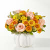 Peach roses and yellow-orange mums arranged in a white pumpkin vase