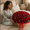 Woman sitting beside a large basket of red roses
