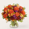 Orange roses and purple mums in a clear glass vase