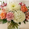 Mixed bouquet of pink and peach flowers in a clear glass vase