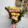 Bouquet of yellow and pink roses wrapped in pink paper with a satin ribbon