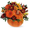 Autumn floral arrangement in a pumpkin-shaped container with orange and red blooms